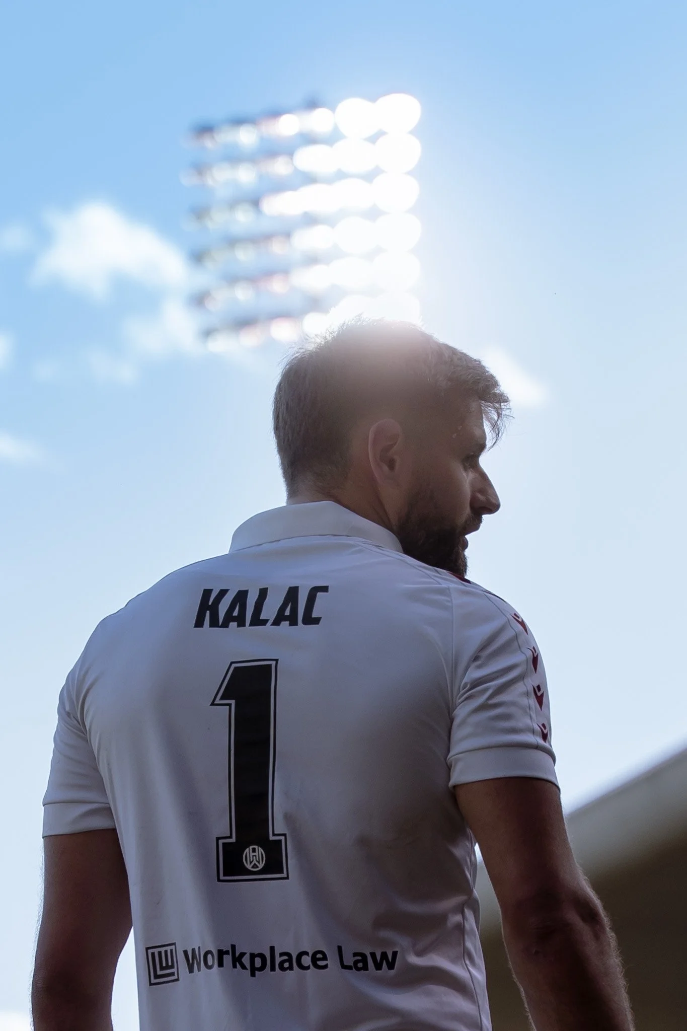 Player in white KALAC jersey under stadium lights