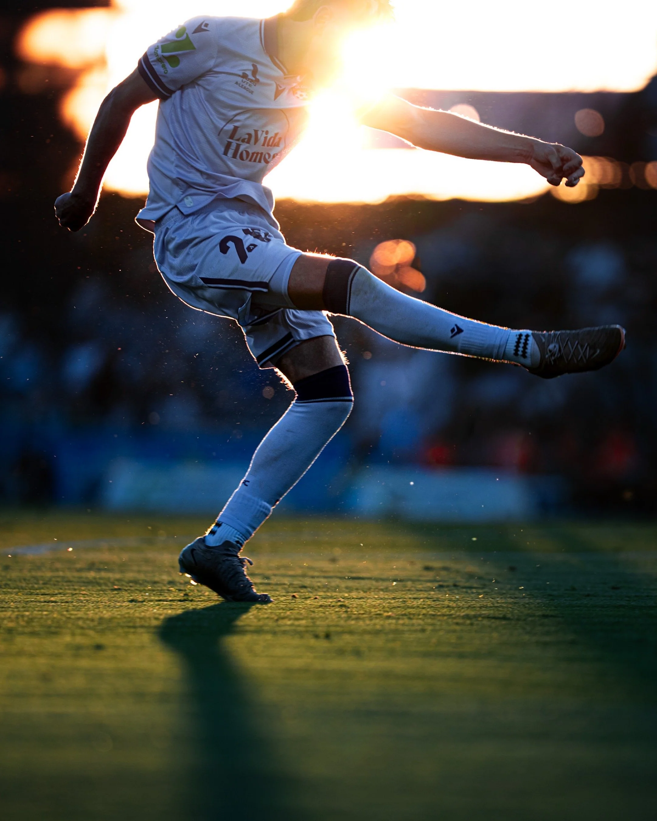 Player kicking a ball at sunset