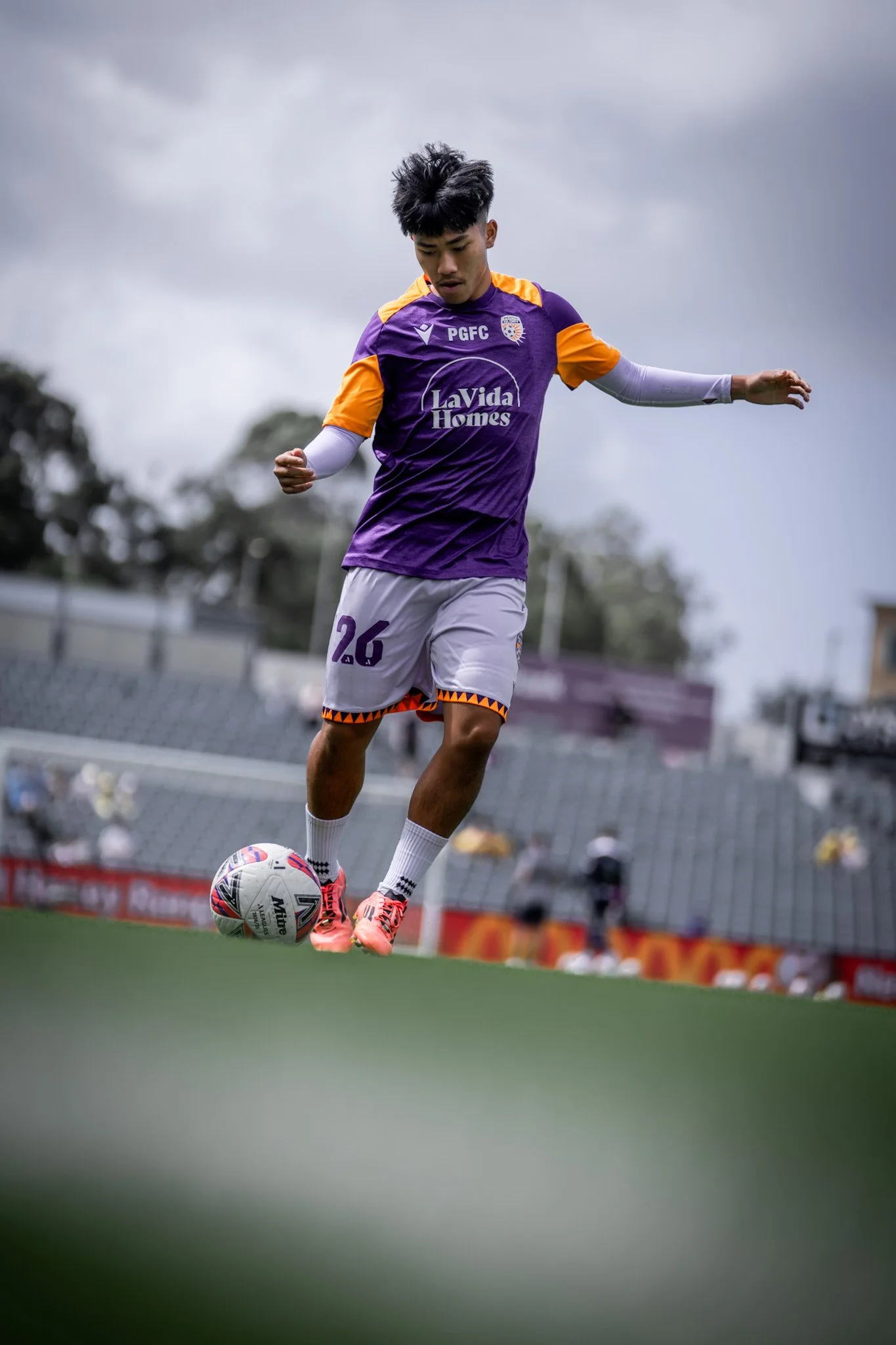Young player dribbling with cloudy sky