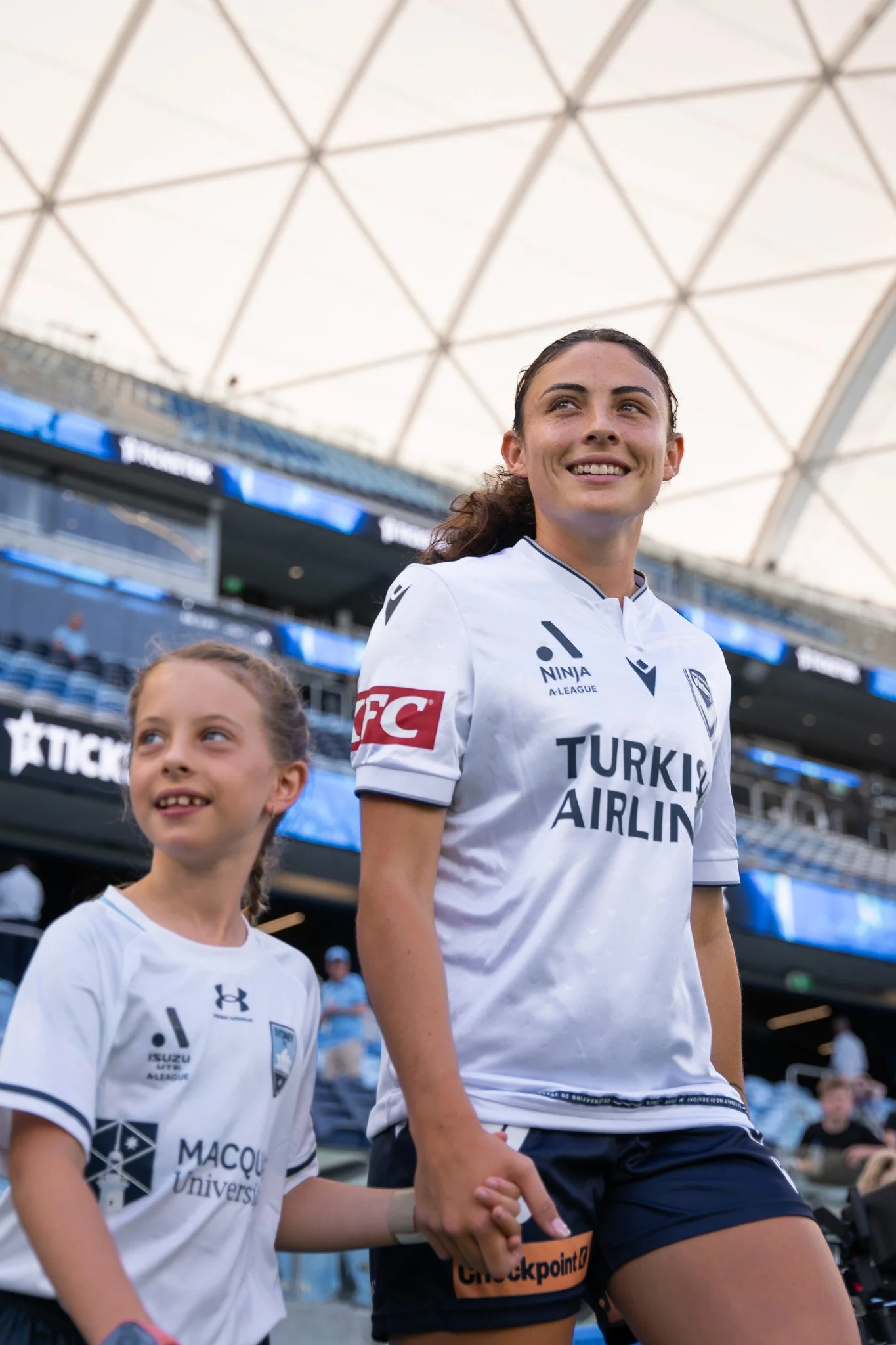 Player and child holding hands in stadium