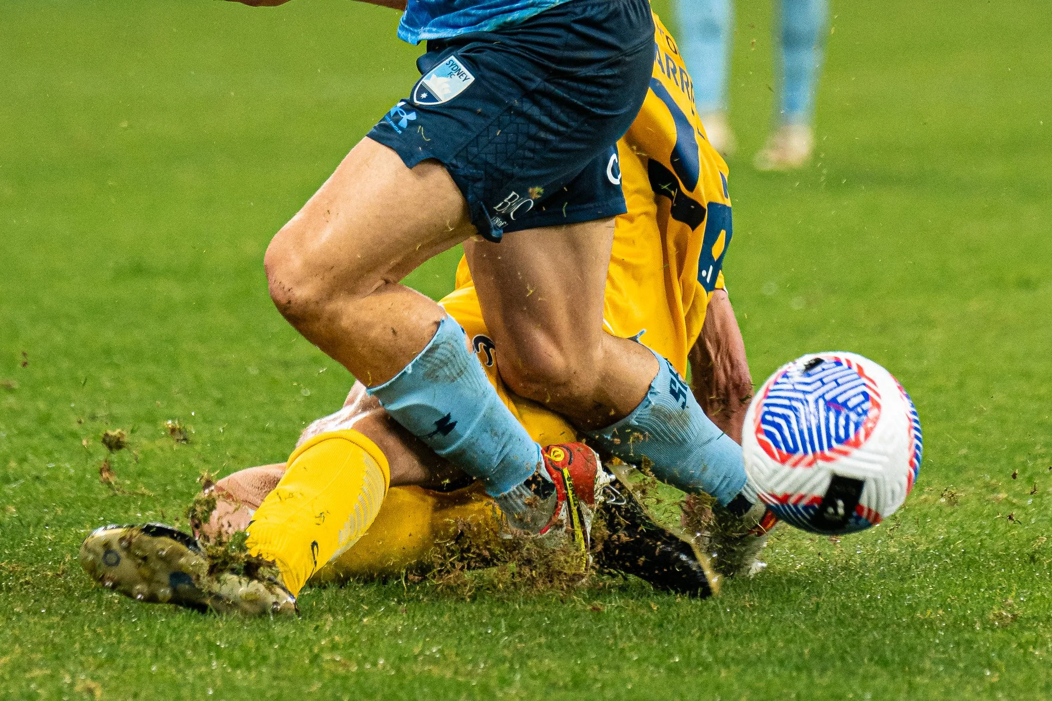 Two players sliding for the ball