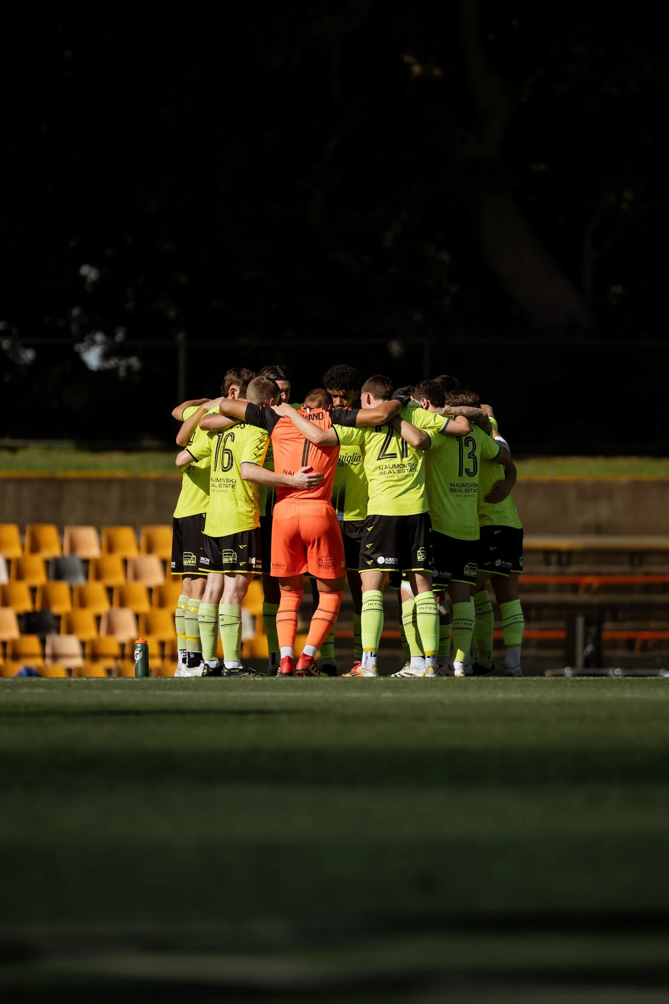Team huddling in yellow jerseys at dusk
