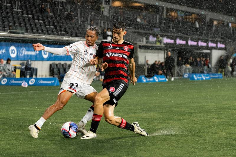Soccer player mid-stride chasing the ball on a floodlit pitch