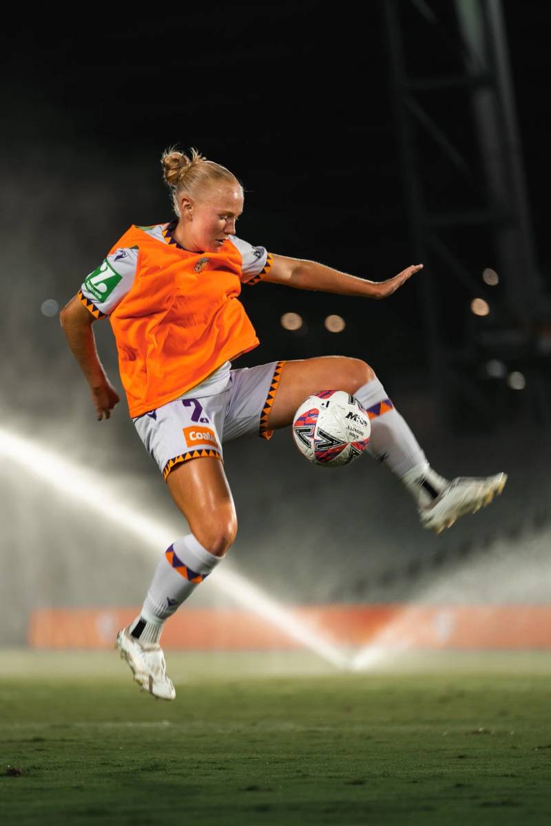 Female soccer player mid-air controlling the ball