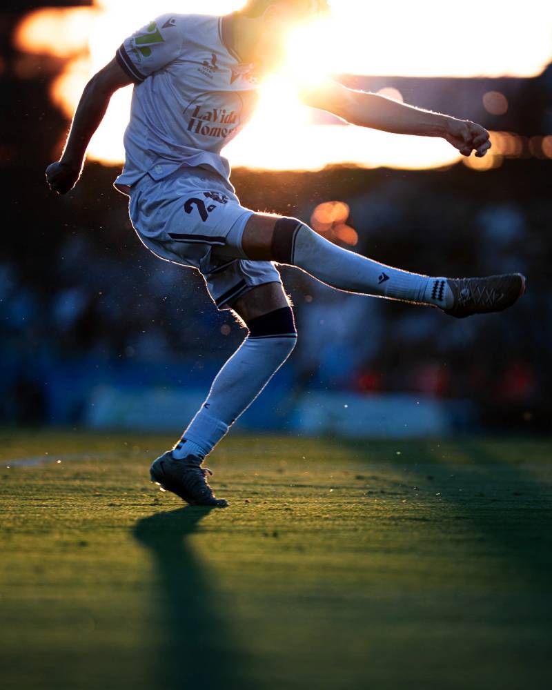 Player kicking a ball at sunset