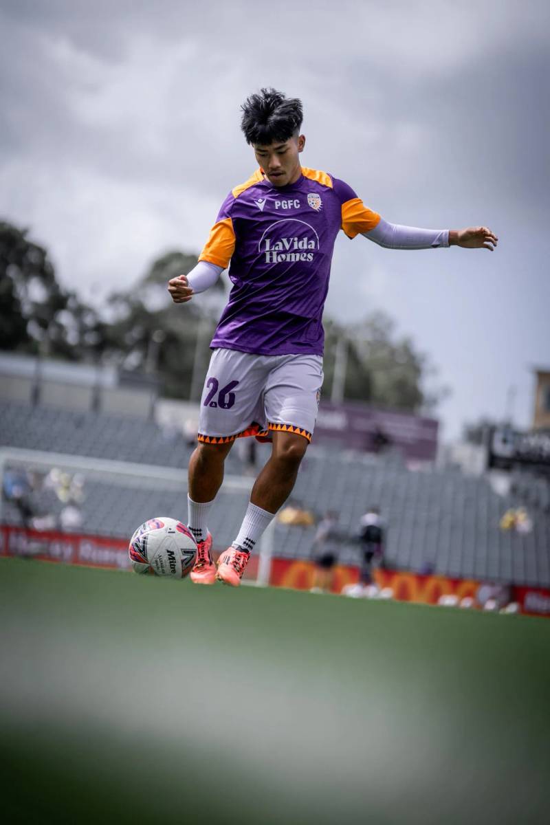 Young player dribbling with cloudy sky
