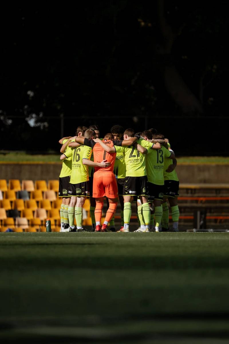 Team huddling in yellow jerseys at dusk